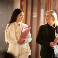 two women walking and talking in an office corridor