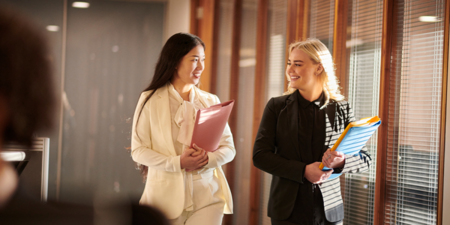 two women walking and talking in an office corridor