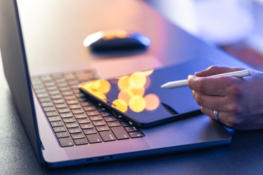 Image of close up of hand working on tablet and laptop