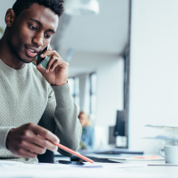 Black office worker dressed in a grey jumper on the phone