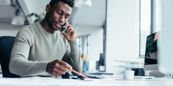 Black office worker dressed in a grey jumper on the phone