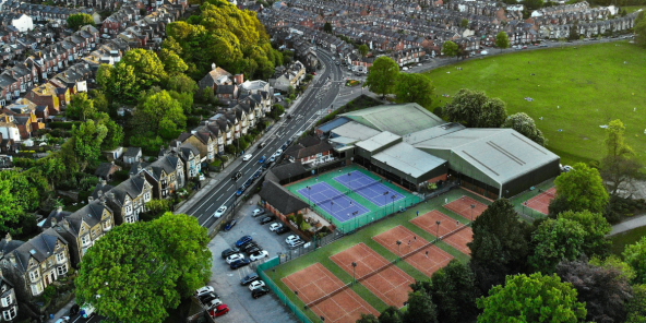 Aerial view of a suburban neighbourhood in Sheffield with tree-lined streets and a sports complex featuring tennis courts, a swimming pool, and a green field.