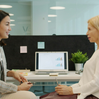 two women discussing data at their desks
