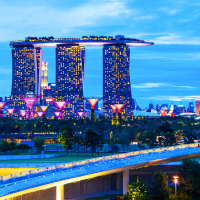The Singapore skyline at twilight, featuring the Marina Bay Sands hotel, Gardens by the Bay, and other illuminated skyscrapers.