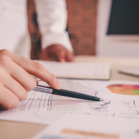 a closeup of a hand holding a pen while examining stats
