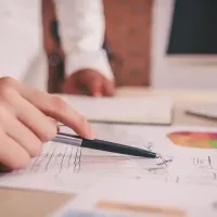 a closeup of a hand holding a pen while examining stats