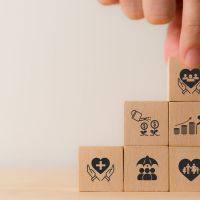 A hand placing a stack of wooden blocks printed with icon benefits