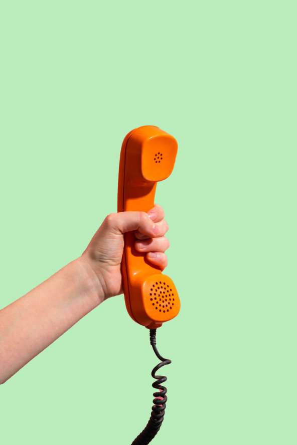 a hand holding a coral-coloured rotary phone handset