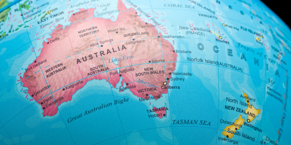 A blue world map focused on Australia, showing surrounding oceans and nearby islands, with labelled regions and borders on a globe-like projection.