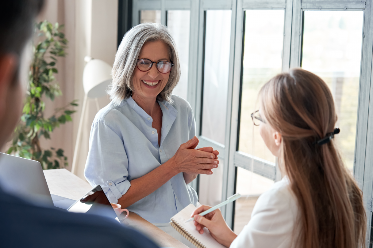 A smiling female older mentor interacting with co-workers in an office