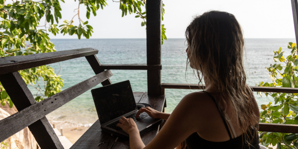 Digital nomad woman working on the beach