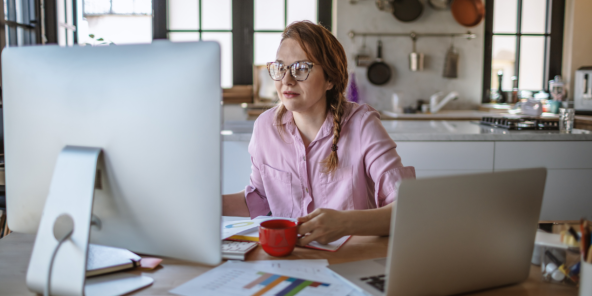 woman wearing a pink shirt, remote working from her kitchen desk