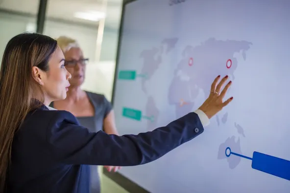 two women studying world map on screen