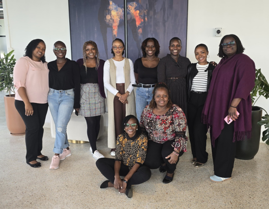 A group of women from Mauve's Kenyan office posing for a photo indoors, with some standing and others kneeling.