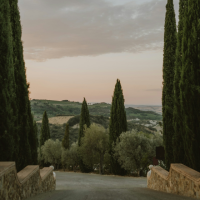 A Tuscan-style countryside with a stone walled driveway at sunset