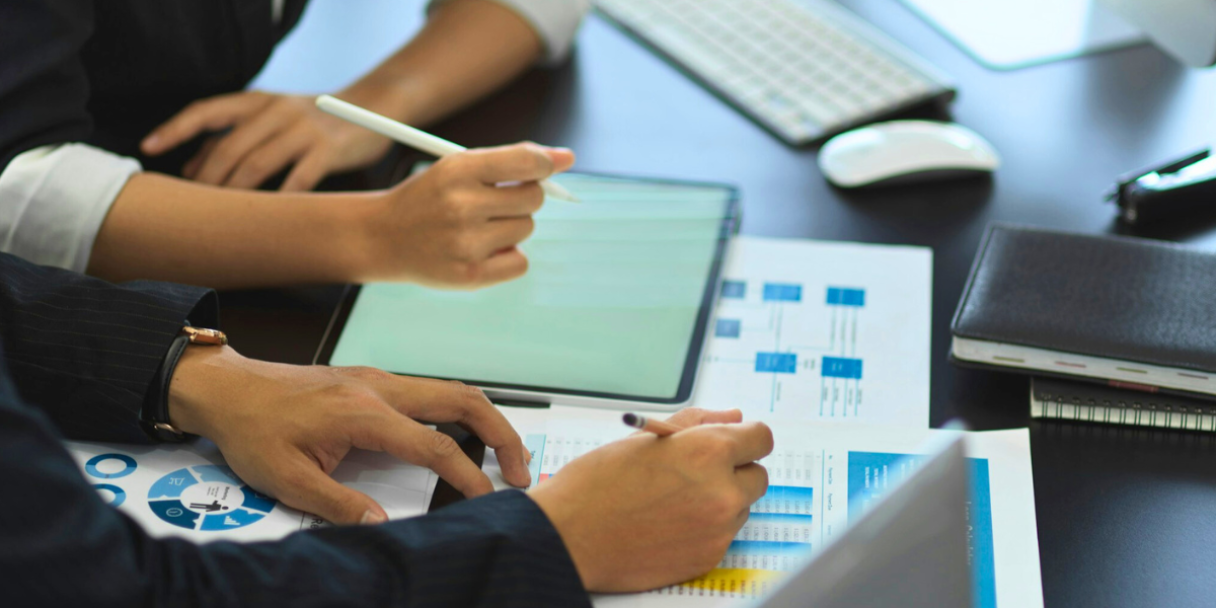 side view of two businesspeople consulting on their work with business charts
