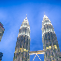 The Petronas Twin Towers in Kuala Lumpur illuminated at night against a deep blue sky.