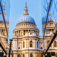 St. Paul's Cathedral in London is reflected in the glass facade of a modern building.