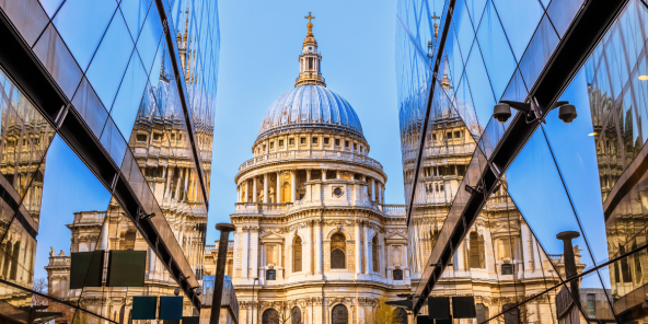 St. Paul's Cathedral in London is reflected in the glass facade of a modern building.