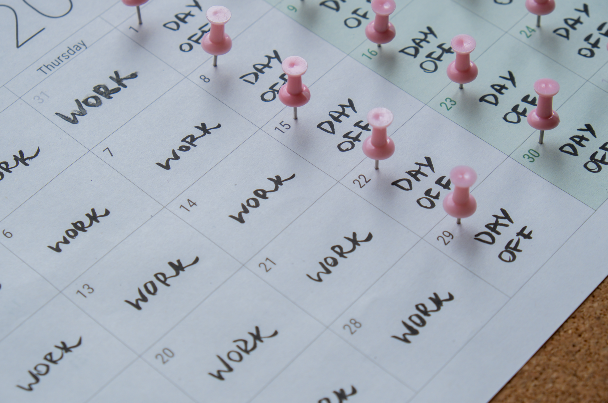 A calendar with pink push pins