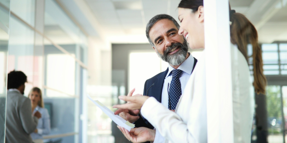 colleagues in business attire are looking at a document together and smiling in a modern office setting
