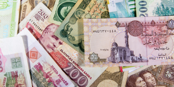 A collection of various international banknotes, featuring different denominations, colours, and imagery including portraits, buildings, and script.