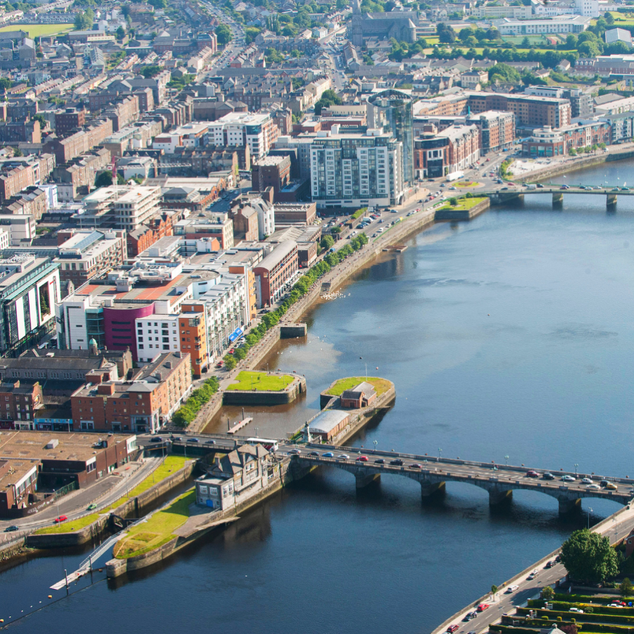 Aerial view of a wide river flowing through a city, with bridges connecting the banks and buildings lining the waterfront.