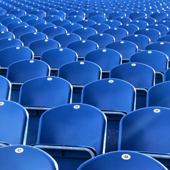 Rows of empty blue stadium seats stretch into the distance.