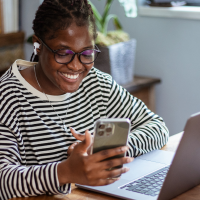 Smiling woman, dressed in a black-white striped top, working remotely