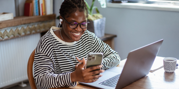 Smiling woman, dressed in a black-white striped top, working remotely