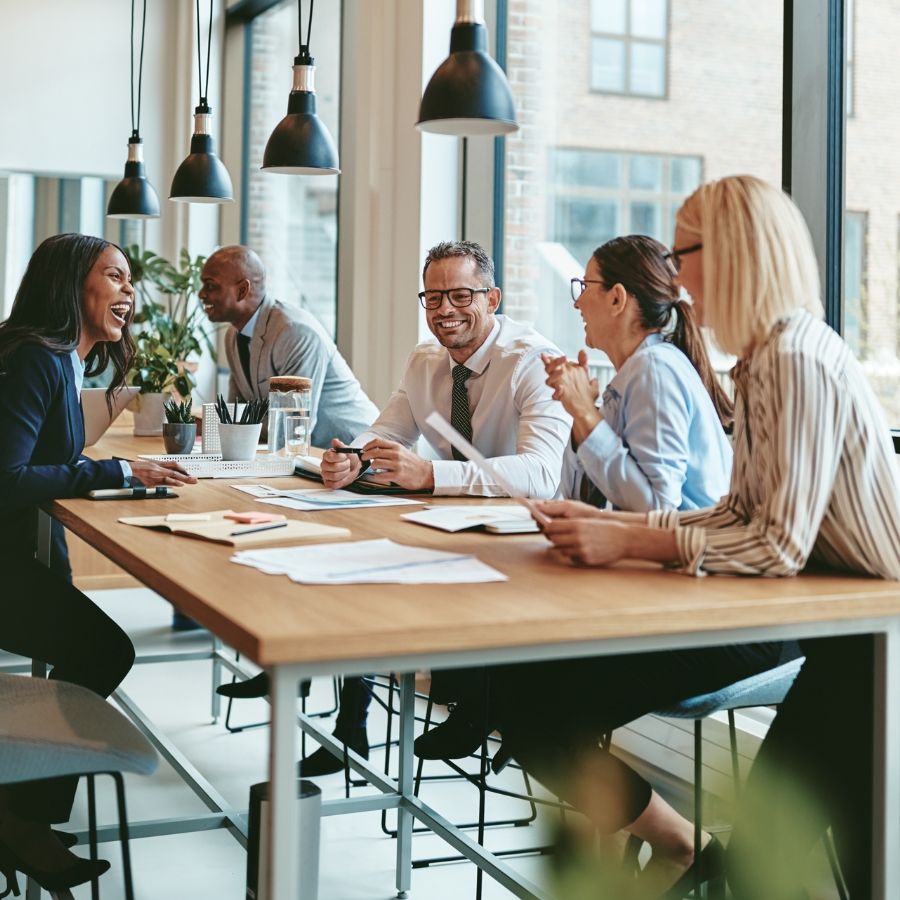 A jovial, diverse team gathered at a desk in the office