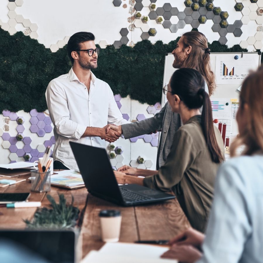 Male office colleagues shakings hands in a meeting