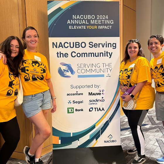 Team Mauve stood near a stand while volunteering at NACUBO