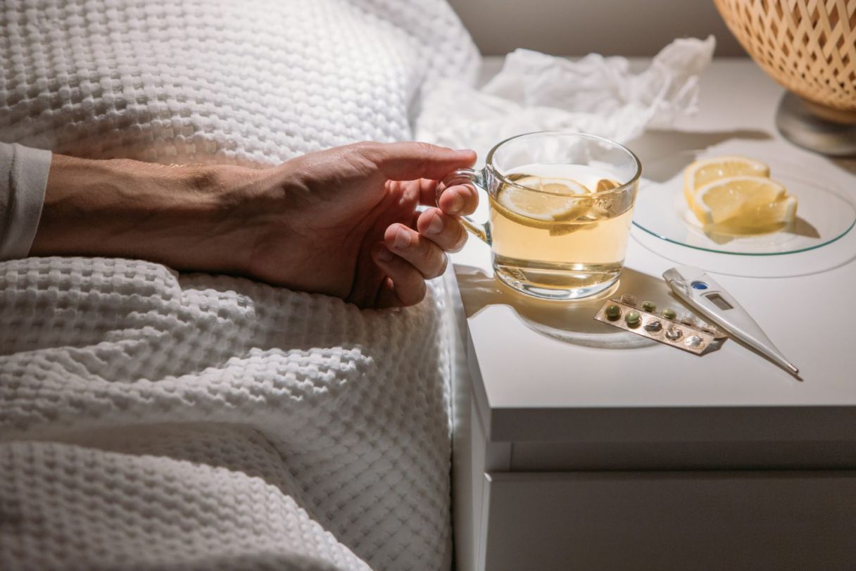 sick-man-bed-holding-cup-hot-tea-with-lemon-drinking-hot-beverage-get-well-from-flu-fever-virus