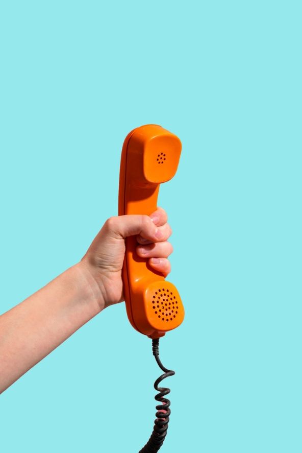 A hand holding a red phone against a neon blue background