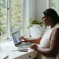 a woman working on her laptop in front of a window