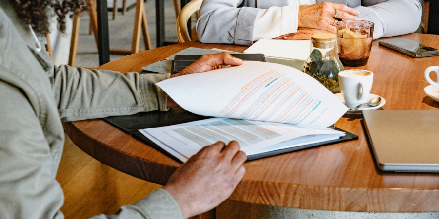 two colleagues sitting at a table with a laptop and discussing legal papers