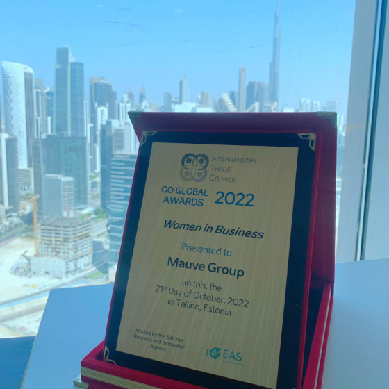 The Go Global Awards 2022 plaque presented to Mauve Group for 'Women in Business' in 2022 in Tallinn, Estonia, placed on a window ledge with Dubai's cityscape in the background.