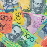 A close-up overhead view of various Australian dollar banknotes scattered and overlapping, including denominations of 10, 20, 50, and 100.