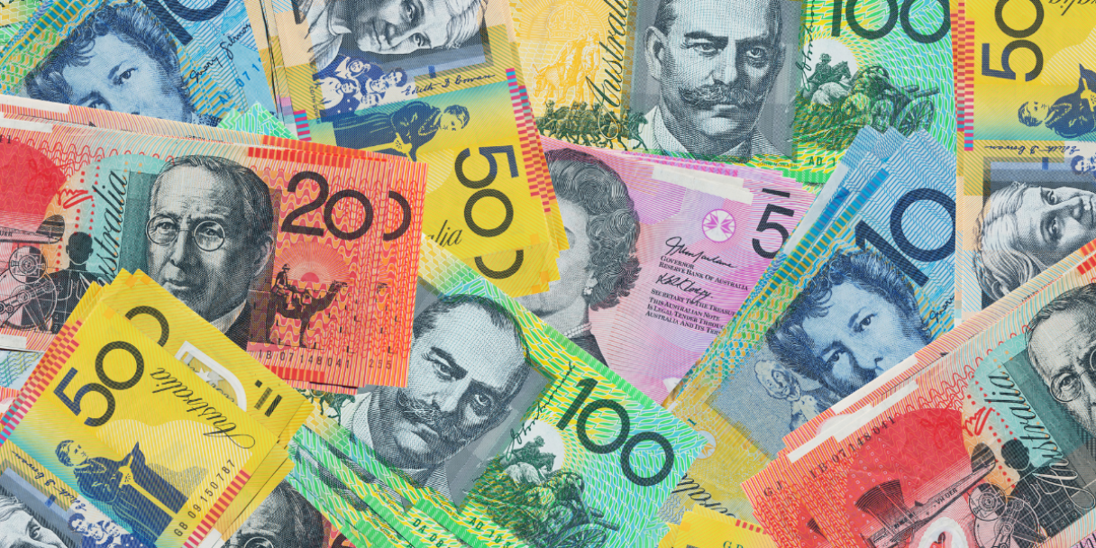 A close-up overhead view of various Australian dollar banknotes scattered and overlapping, including denominations of 10, 20, 50, and 100.