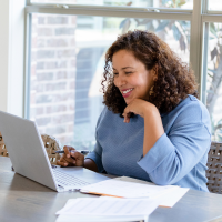 Smiling lady dressed in a blue jumper while in a virtual meeting while working from home