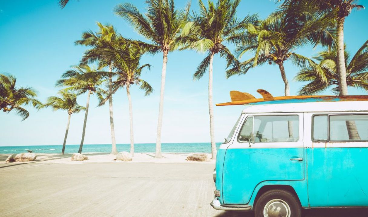 vintage-car-parked-tropical-beach-with-surfboard-roof