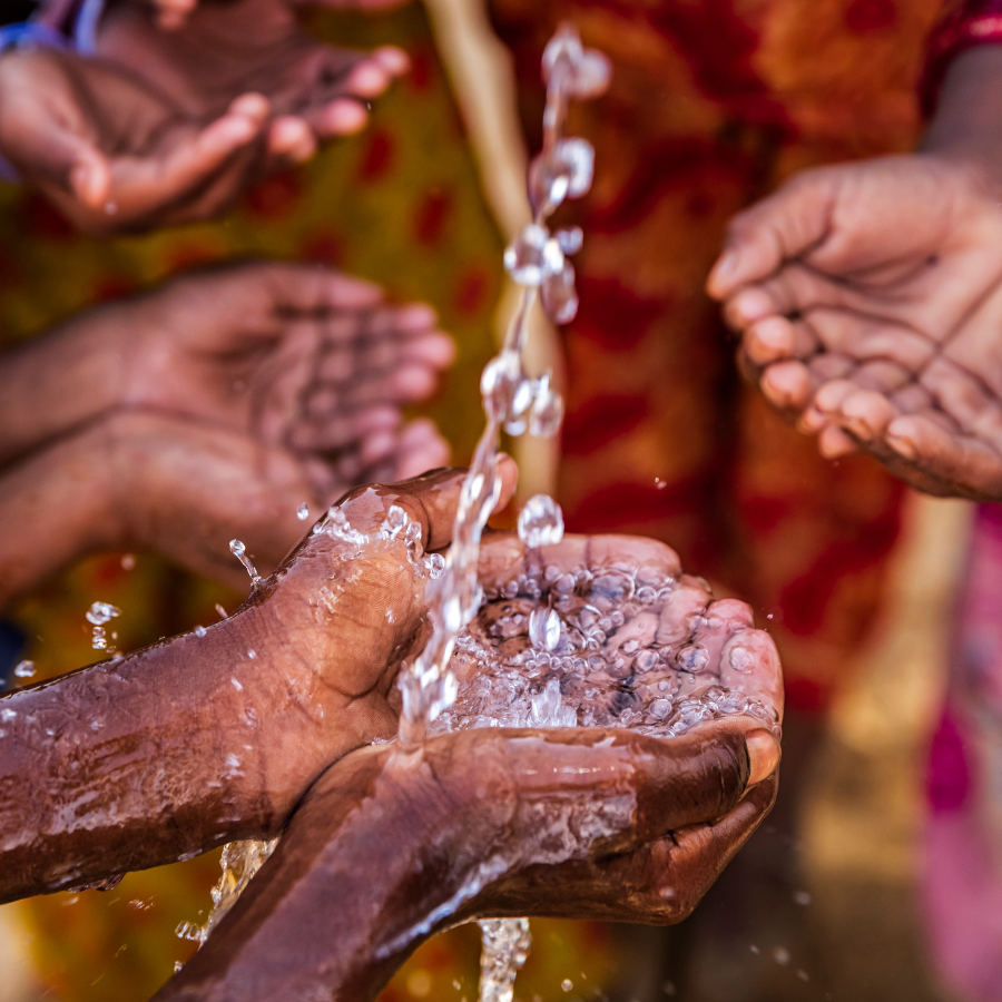 A close-up of African children running their hands under a water supply