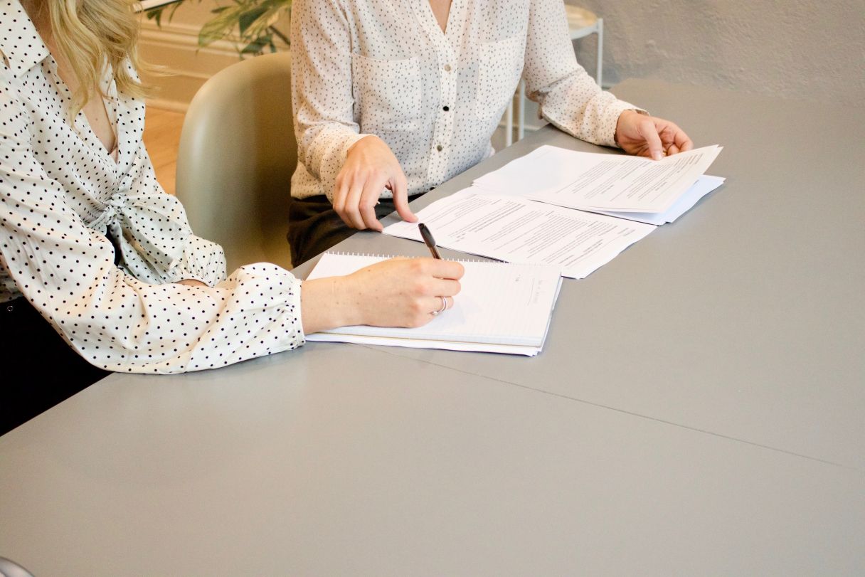 Mujeres discutiendo documentos oficiales y tomando notas