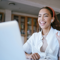 Mujer sudamericana sonriendo y saludando a la pantalla de un portátil mientras participa en un seminario web.