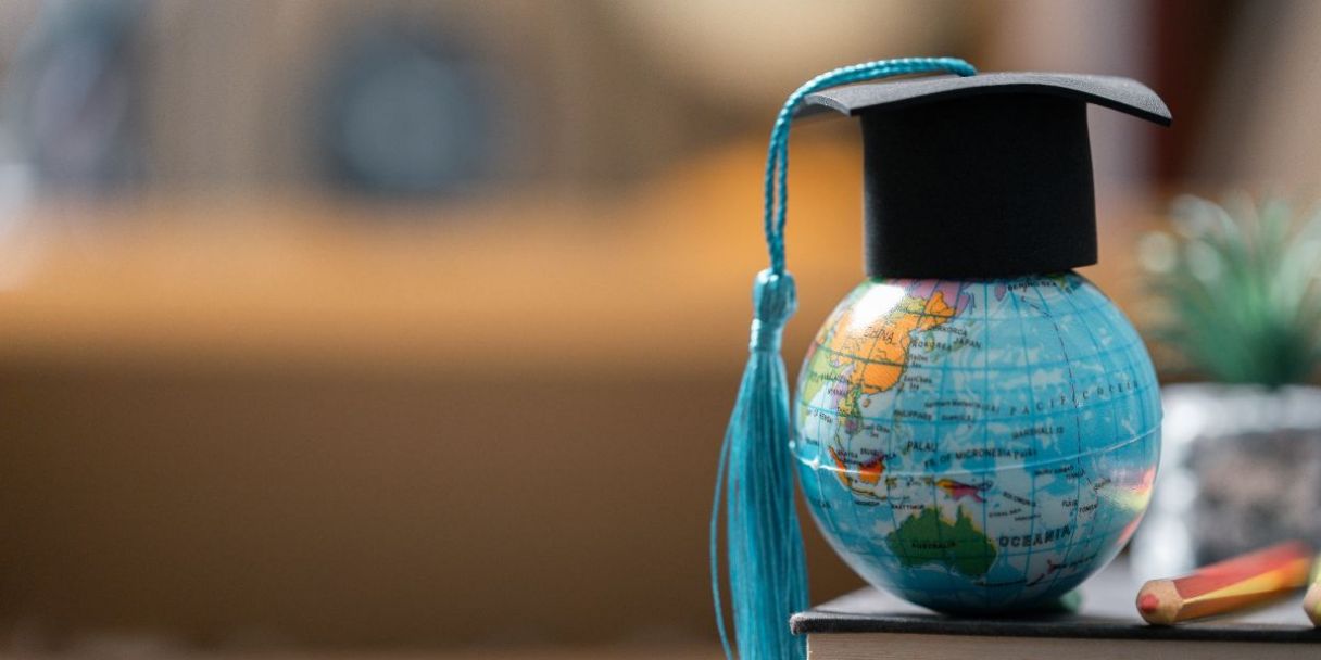 un birrete de graduación sobre un globo terráqueo en miniatura