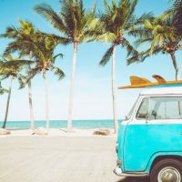 vintage-car-parked-tropical-beach-with-surfboard-roof